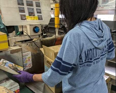 女性スタッフも多数活躍中！箱から取り出した本の付録を外して所定の位置にセットするだけ！